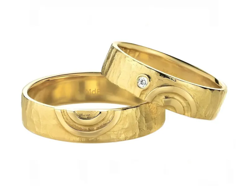 Anillos de matrimonio de oro amarillo texturizado con diseño geométrico y piedra.