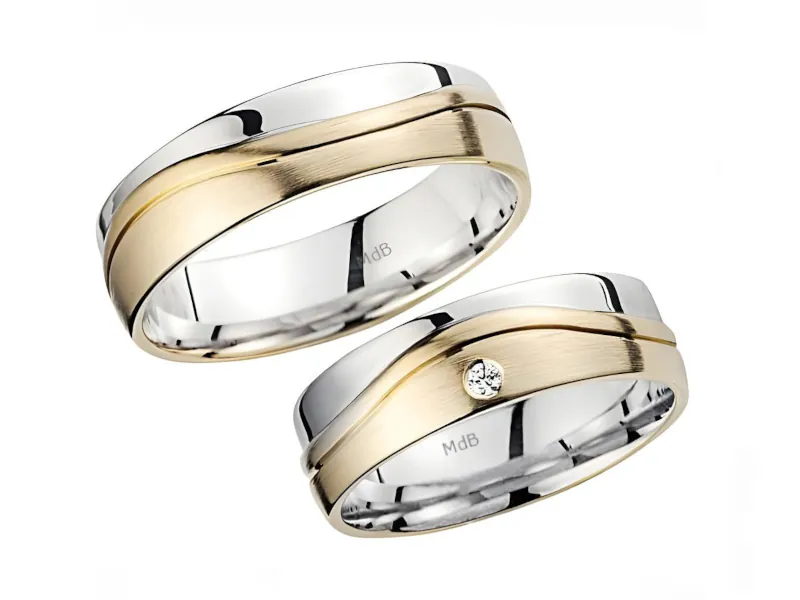 Par de anillos de boda de dos tonos con banda central dorada mate y bordes brillantes en oro blanco. Un anillo incluye una pequeña piedra engastada