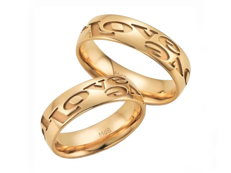 Par de anillos de boda en oro amarillo con letras grabadas en la superficie