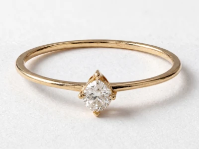 Anillo de promesa en oro amarillo 18k con piedra central redonda engastada en garras finas, diseño minimalista.