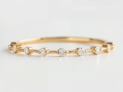 Anillo de promesa en oro amarillo 18k con diamantes redondos engastados de forma continua, diseño fino y elegante.