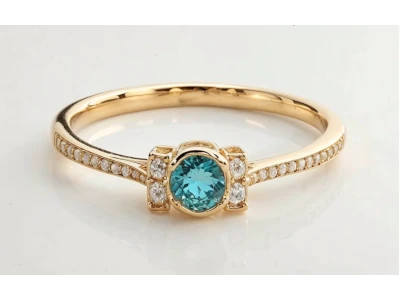 Anillo de promesa en oro amarillo 18k con piedra central azul verdosa y pidras laterales engastados en carril.