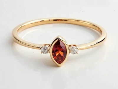 Anillo de promesa en oro amarillo 18k con piedra granate talla marquise y dos piedras laterales engastadas.