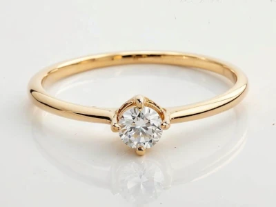 Anillo de promesa en oro amarillo 18k con diamante redondo central engastado en tres garras y banda fina.
