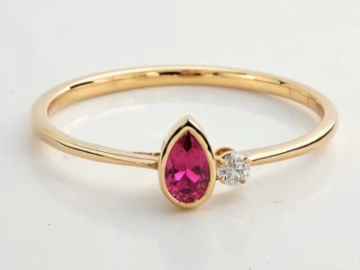 Anillo de promesa en oro amarillo 18k con piedra granate en forma pera y piedras laterales en diseño minimalista.