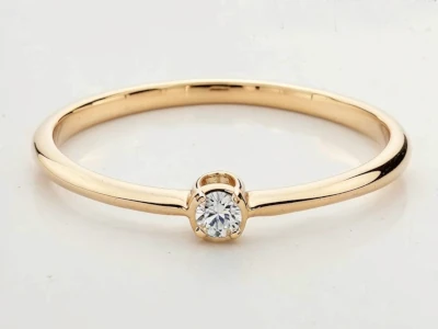 Anillo de promesa en oro 18k con una piedra central engastado en garras, diseño minimalista y delicado.