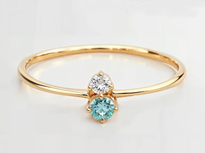 Anillo de promesa en oro amarillo 18k con dos piedras redondas en tonos contrastantes, engaste en garras, diseño delicado.
