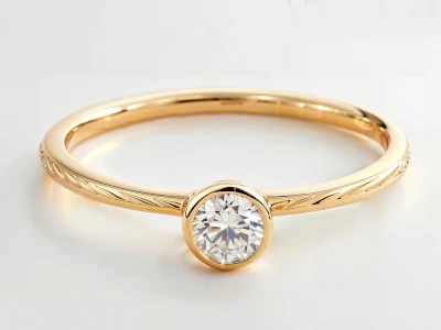 Anillo de promesa en oro amarillo 18k con piedra central redonda y grabado lateral, diseño elegante y artesanal.