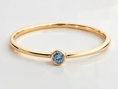 Anillo de promesa en oro amarillo 18k con piedra azul engastada en bisel y banda fina pulida.
