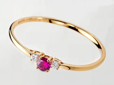 Anillo de promesa en oro amarillo 18k con piedra central color granate y dos piedras laterales engastados.
