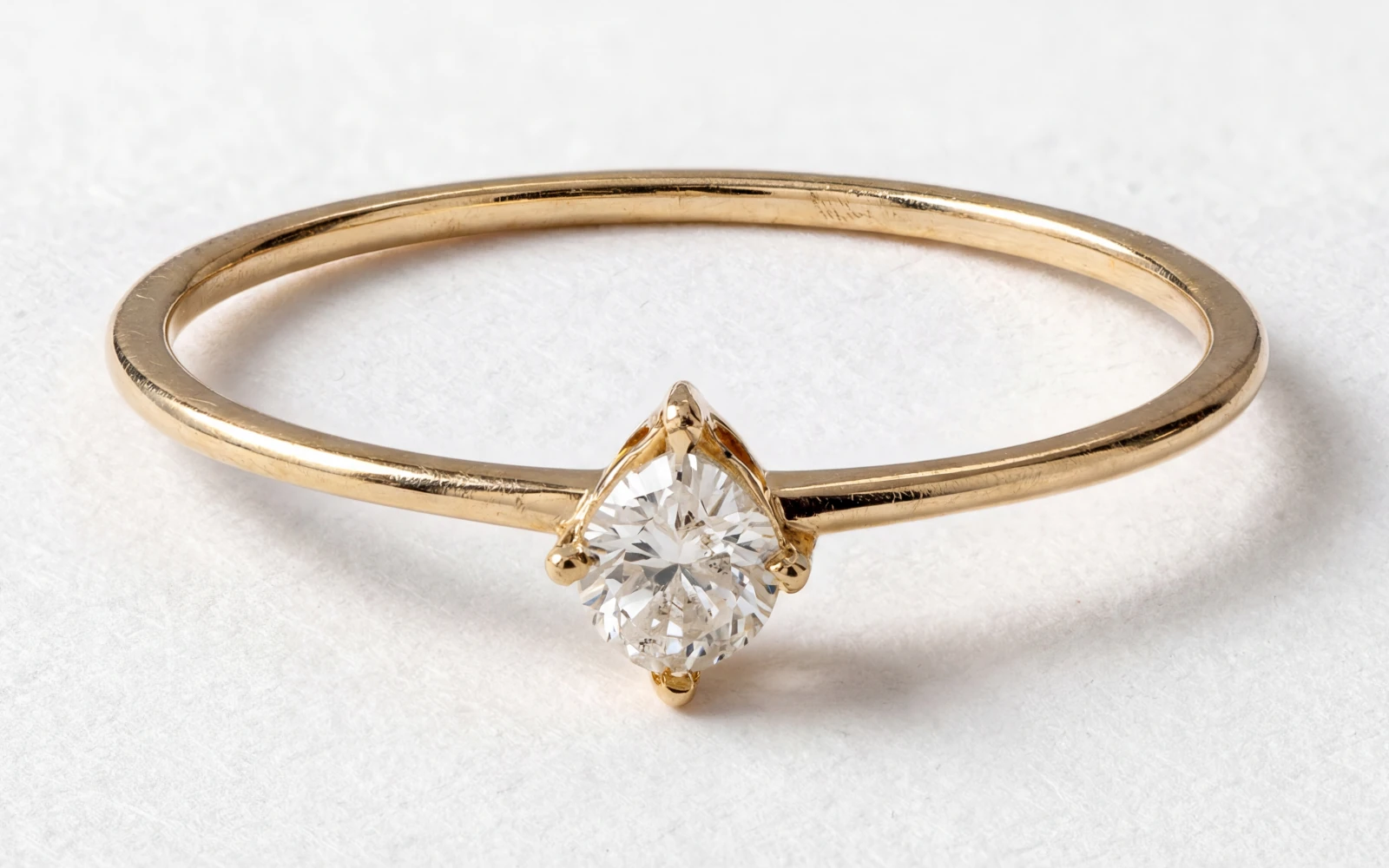 Anillo de promesa en oro amarillo 18k con piedra central redonda engastada en garras finas, diseño minimalista.