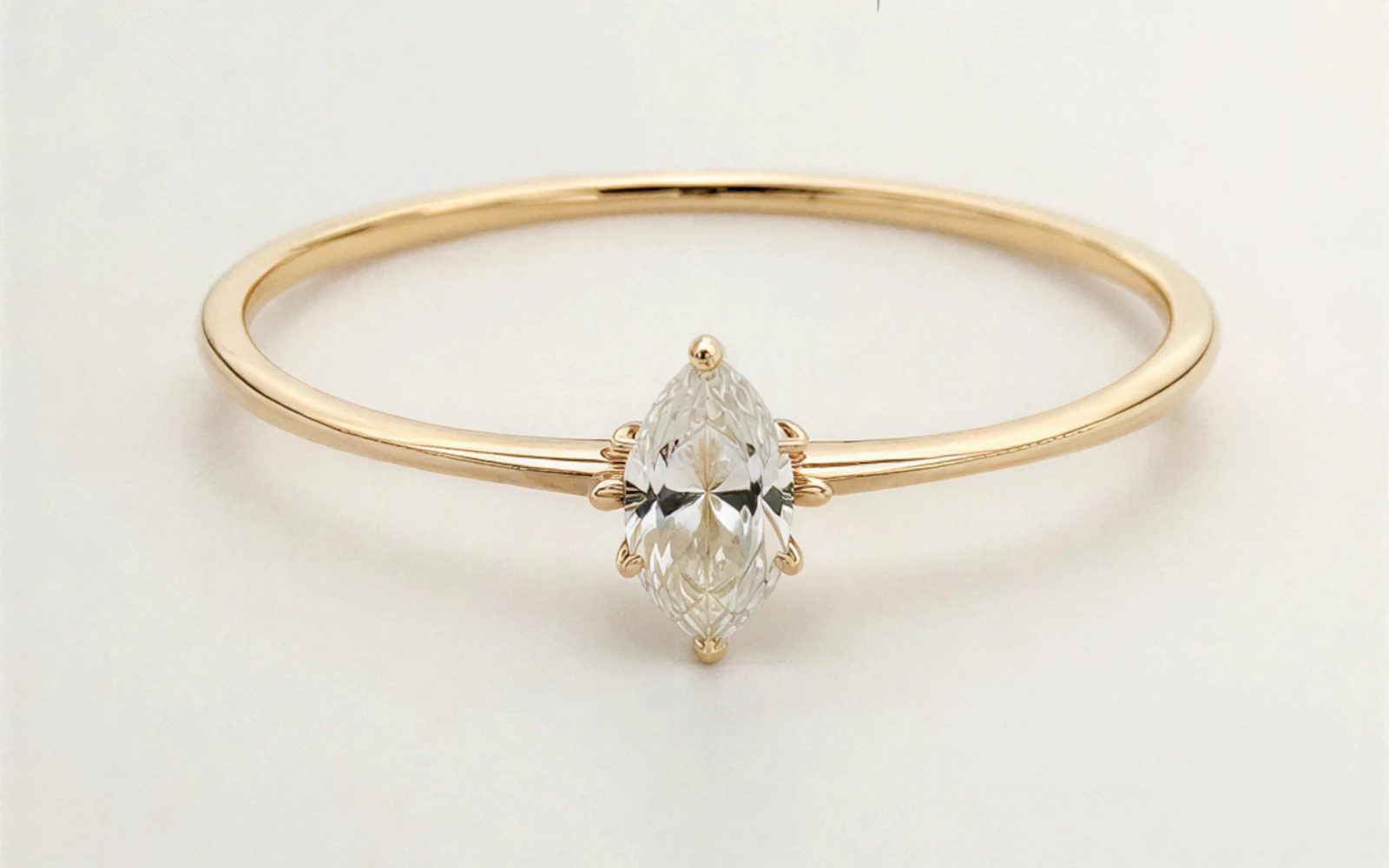 Anillo de promesa en oro amarillo 18k con piedra central marquise engastada en garras, diseño fino y elegante.