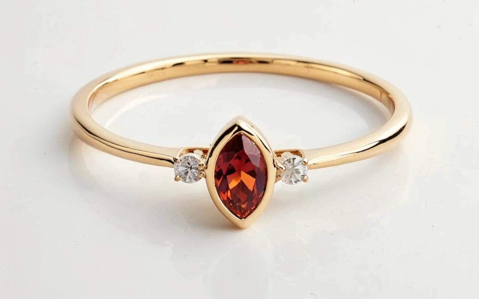 Anillo de promesa en oro amarillo 18k con piedra granate talla marquise y dos piedras laterales engastadas.