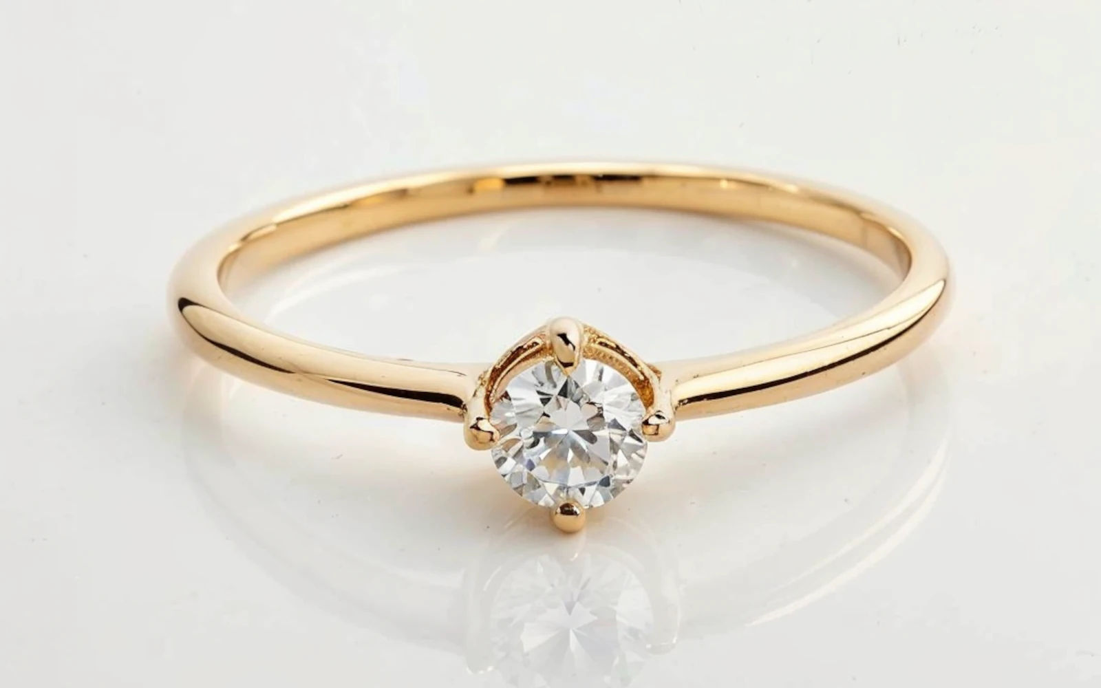 Anillo de promesa en oro amarillo 18k con diamante redondo central engastado en tres garras y banda fina.