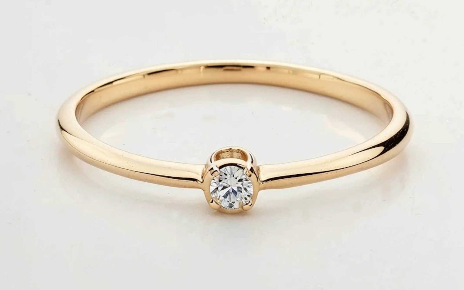 Anillo de promesa en oro 18k con una piedra central engastado en garras, diseño minimalista y delicado.