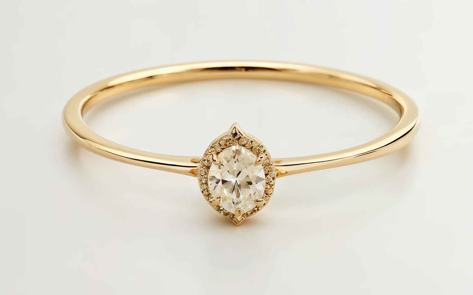 Anillo de promesa en oro 18k con diamante en forma oval y halo de piedras, diseño delicado y elegante.