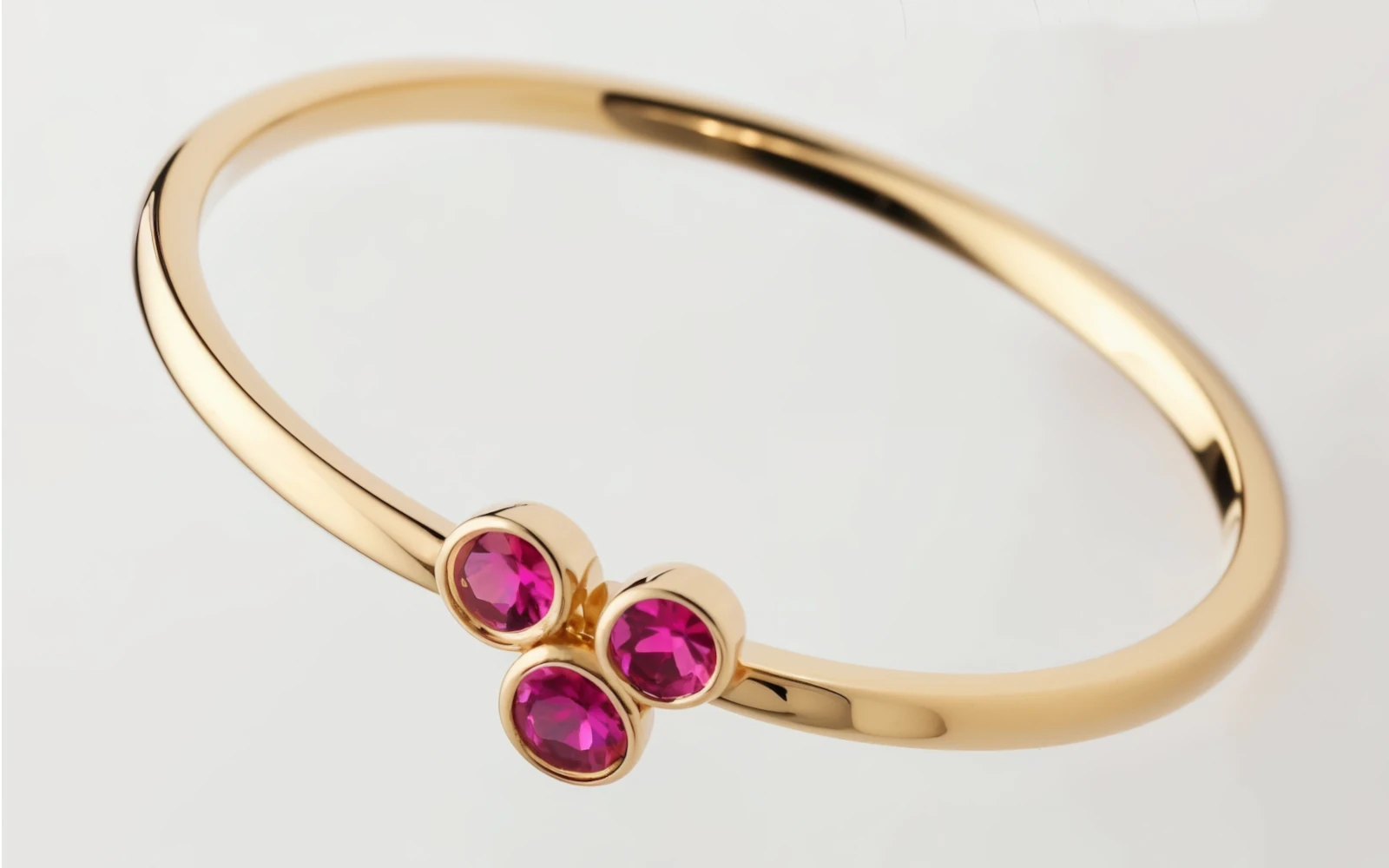 Anillo de promesa en oro amarillo 18k con tres piedras color granate engastadas en bisel, diseño delicado y moderno.