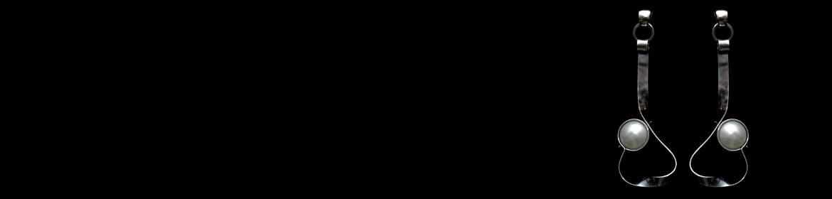 Pendientes de plata con perlas naturales. Esta imagen ilustra la belleza y delicadeza de las perlas, reforzando la importancia del cuidado adecuado que se describe en el post Cuidado para las Perlas Naturales. El fondo negro realza el brillo perlado y la elegancia del diseño.