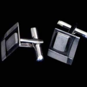 Gemelos de plata con diseño geométrico de la marca [Nombre de la marca, si aplica, o Artesanía en Plata si no se especifica. La imagen ilustra la idea de Estilo Eres Tú, representando cómo los accesorios pueden reflejar la personalidad y el estilo individual. El fondo negro resalta la elegancia y los detalles de las piezas.