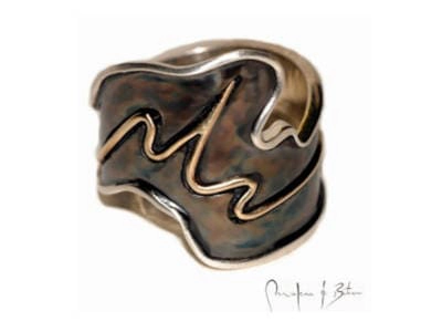 nillo artesanal con diseño ondulante en plata patinada, mostrando formas orgánicas y fluidas características del trabajo manual, firmado por el artista joyero