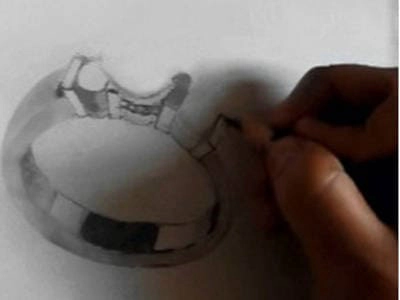 Primer plano de una mano dibujando el boceto detallado de un anillo de compromiso, mostrando el proceso creativo de diseño personalizado en joyería nupcial
