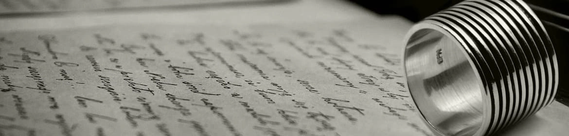 Imagen en blanco y negro de un anillo moderno con diseño acanalado sobre una carta manuscrita, simbolizando la fusión entre la joyería contemporánea y las emociones personales