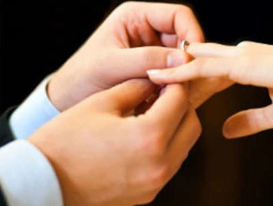 Manos de una pareja intercambiando anillos de boda en una ceremonia, simbolizando el compromiso y la unión.

