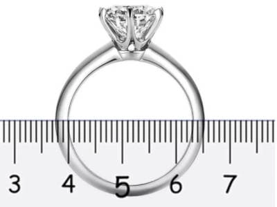 Anillo de compromiso solitario sobre una regla de joyería, mostrando la medición del diámetro interno entre las marcas de 5 y 6 centímetros, ilustrando el método para determinar la talla del anillo