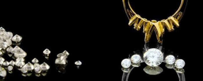  Imagen que muestra un anillo de oro amarillo con diamantes, junto a varios diamantes sueltos, ilustrando las partes estándar que conforman un anillo.