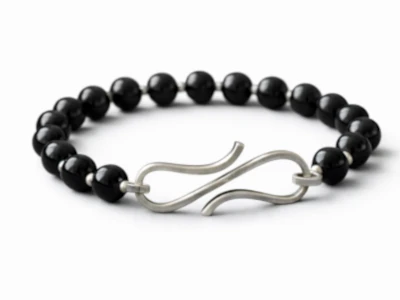 Pulsera de ónix negro con broche de plata sobre fondo de tela elegante