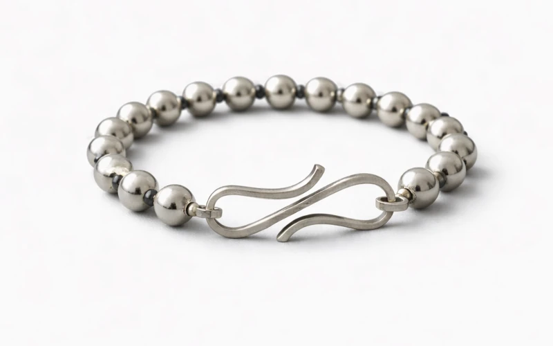 Pulsera de plata artesanal con cierre curvado elegante sobre fondo negro satin