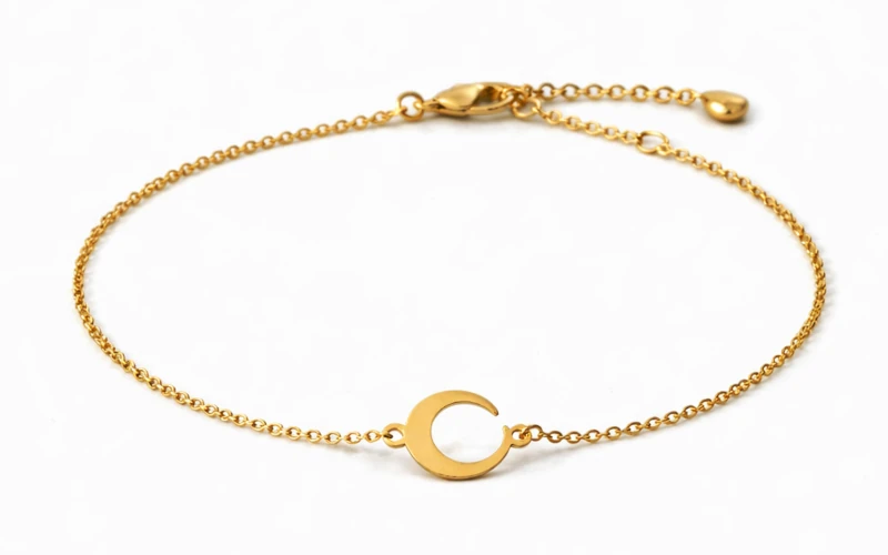 Pulsera de luna dorada minimalista sobre fondo negro, joya elegante para mujer