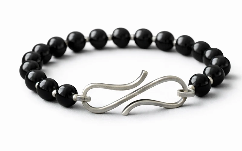 Pulsera de ónix negro con broche de plata sobre fondo de tela elegante