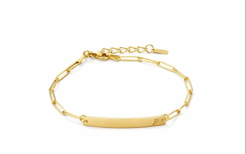 Pulsera de oro con placa grabada y diseño minimalista sobre fondo oscuro